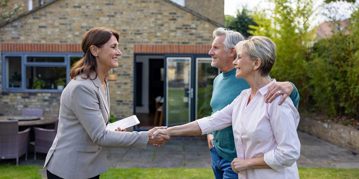 Couple meeting with real estate agent outdoors.